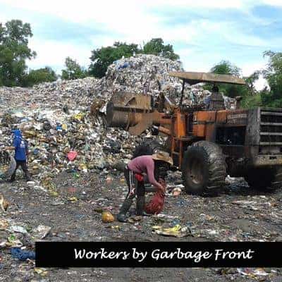 Workers close to machinery near dump front. 