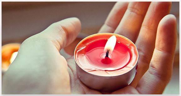 Lit candle in palm of hand