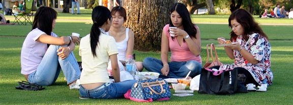 Group of girls sitting in a circle on the grass eating.