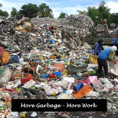 Workers surrounded by rubbish on dump.