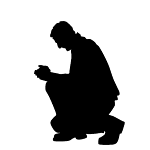 Silhouette of man on one knee praying