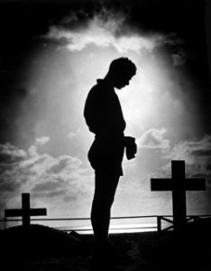 Silhouette of Man standing at a grave.
