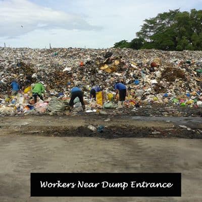 Workers at the front end of a garbage dump.