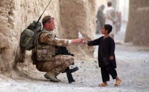 Soldier and young boy sharing a bottle of drink