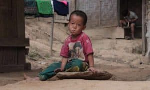 Child in poor community sitting in street